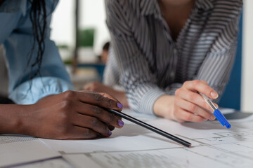 Closeup of architectural engineer hands holding pencil and pen over blueprints at modern technical drawing desk. Detailed view of architects inspecting construction plans of residential project.