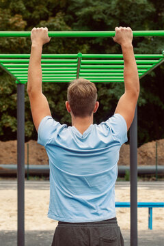A young guy doing exercises on the bar. The concept of sports, healthy lifestyle