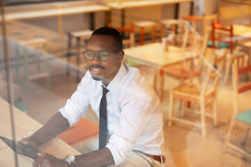 Businessman drinking coffee in cafe. Handsome African man using digital tablet while enjoy in fresh coffee