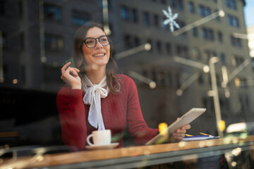 Happy woman using credit card to shopping online with tablet. Beautiful young woman drinking coffee in cafe.