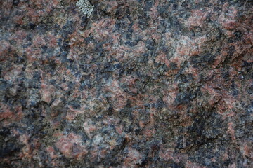 Grey dry concrete marble stone with red-black inclusions structured uneven surface close-up industrial rough textured background