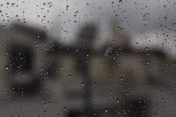 Rain drops on the glass in the spring afternoon. Close up of a window with rain drops falling down.The rain drops on household windows. Focus on rain drops. concept of sadness, frustration