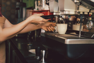 Fototapeta na wymiar Female barista making cup of coffee with coffee machine in cafe.