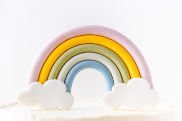 Birthday cake with white cream cheese frosting decorated with colorful mastic rainbow on the white background