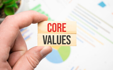 Plakat Cropped view of hands holding wooden cube with Core Values lettering on work table. Top view