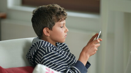 Young boy playing game with tablet. Child plays video-game on tech device
