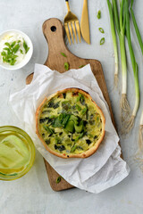 Leek vegetarian tart with cheese on wooden cutting board. Quiche with leek and cheese.