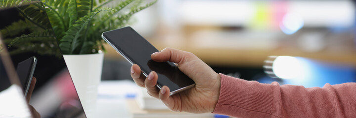 Female hands work on laptop and hold smartphone closeup