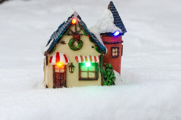 Toy house with lights in the snow. Winter, holiday atmosphere
