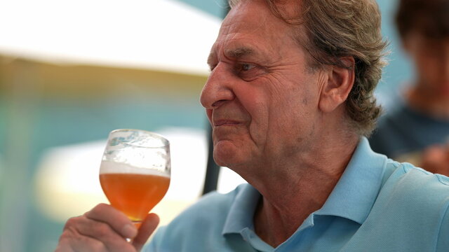 Senior Person Taking A Sip Of Draft Beer