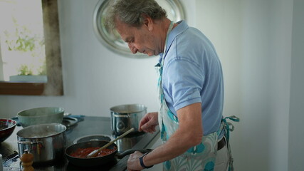 Senior man cooking in kitchen, older person stirring pot preparing food