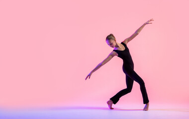 Fototapeta na wymiar Young teenager dancer dancing on a red studio background. Ballet, dance, art, modernity, choreography concept