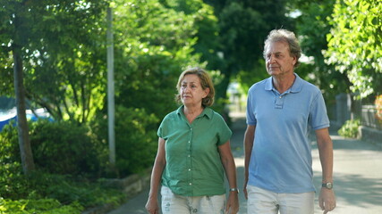 Senior couple walking together outdoors. 60s husband and wife walk