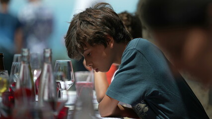 Pensive child sitting at restaurant. Thoughtful young boy