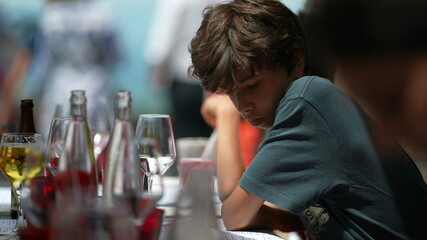 Pensive child sitting at restaurant. Thoughtful young boy