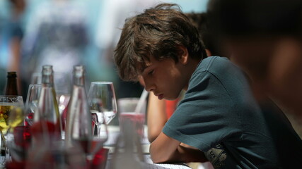 Pensive child sitting at restaurant. Thoughtful young boy