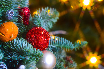 Shiny Christmas tree toys hang on the Christmas tree against the background of lights