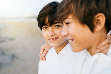 Portrait of two preteen brothers wearing white hooded sweater on the beach, on winter - Powered by Adobe