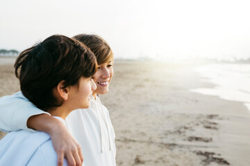 Portrait of two preteen brothers wearing white hooded sweater on the beach, on winter