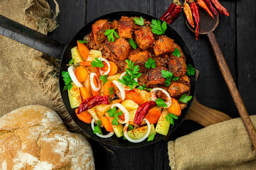 Stew with meat and vegetables in black iron dish. Traditional  gourmet goulash in a rustic kitchen....