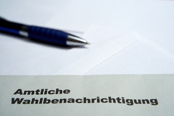 Black letters on white envelope saying: Official election notification (german: Amtliche Wahlbenachrichtigung). 2021 federal election in germany. Blue pen depth of field. Closeup.