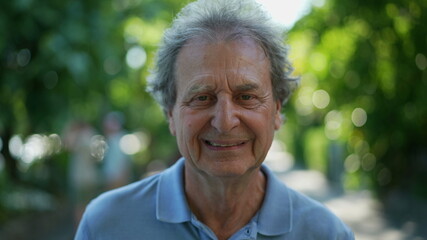 Happy senior man walking forward smiling. One older person walks in green urban city