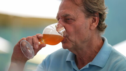 Fototapeta premium Happy senior man drinking beer with friends in conversation