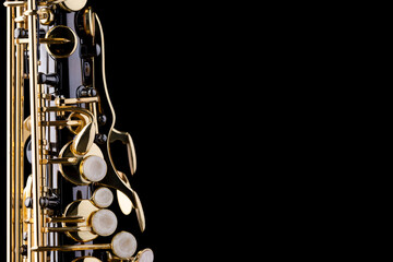 A black saxophone with gold plated keys on a black background