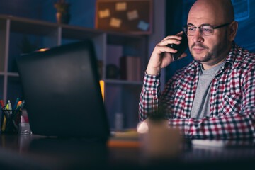 Man having phone conversation while working late
