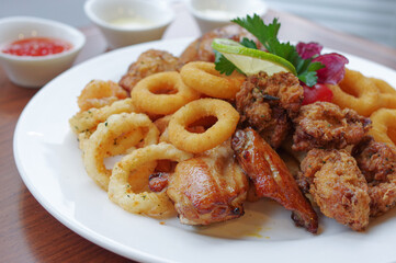 deep fried onion ring squid rings and roasted chicken drumsticks wings nuggets with slice of lime and dips