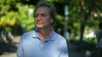 Contemplative senior person walking outside in the sunlight