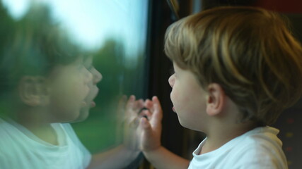 Child traveling by train, little boy staring out train window