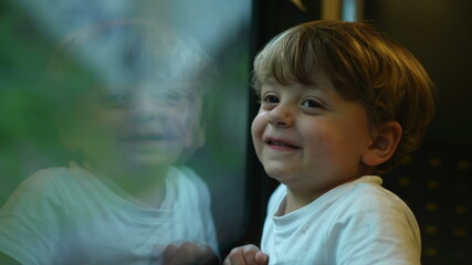 Child traveling by train, little boy staring out train window