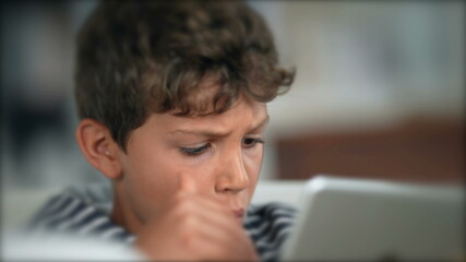 Child surprised reaction holding tablet. Boy WOW face emotion