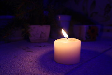 Candle burns on a purple background in the night