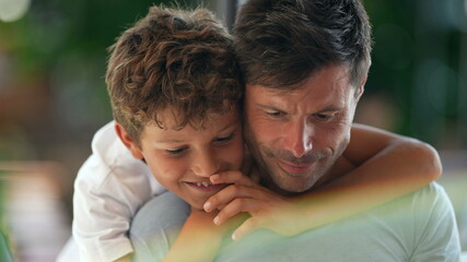 Fototapeta premium Child kissing father on the cheek, candid and real life family love and affection