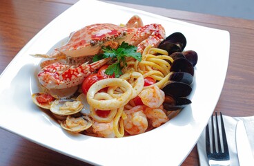 Seafood tomato sauce spaghetti with whole crab, mussels, squid rings, shrimps, clams high angle view