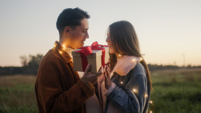 Giovane coppia ragazzo e ragazza con luci led festeggia il san Valentino in un parco naturale