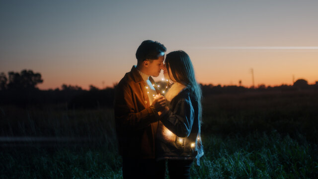 Coppia di ragazzo e ragazza si abbraccia in campagna di notte con striscia di luci led