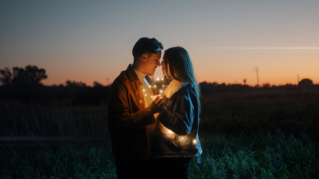 Coppia di ragazzo e ragazza si abbraccia in campagna di notte con striscia di luci led