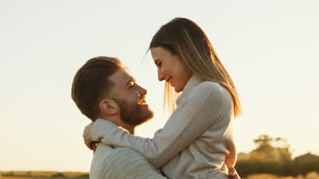 Ragazzo e ragazza si abbracciano e si guardano l'uno con l'altro controluce al tramonto in campagna