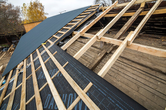 Kyiv, Ukraine - August 25, 2018: Roof frame of wooden beams. Roofing underlayment, water-resistant waterproof barrier material, protection from severe weather and steel roofing profiles.