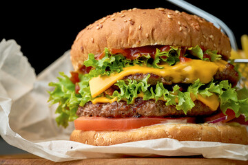 Double burger with cheese, tomato onions and fries on dark background