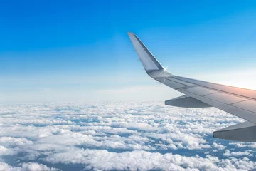 Verduisterende gordijnen Airplane wing above the clouds. View from airplane window. Air travel and transportation concept.  © Nancy Pauwels