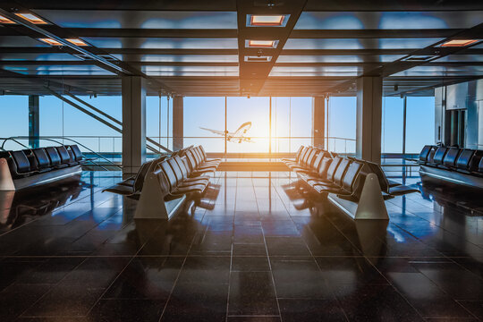 Airport departure hall with empty waiting seats. Plane at sunrise background. Travel and transportation concept.