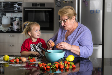 Grandmother and granddaughter together prepare a dish according to grandmother's signature recipe.
