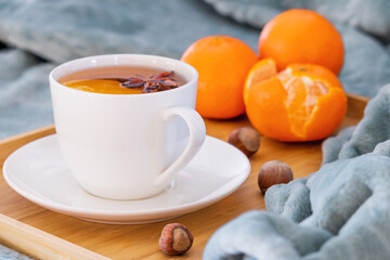 A cup of hot tea with anise star. A cup of fruit tea. Orange tea. Hazelnuts and tangerines. Cozy blanket.