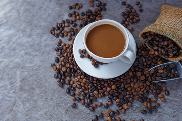 Coffee cup and roasted coffee beans in brown bag, top view.