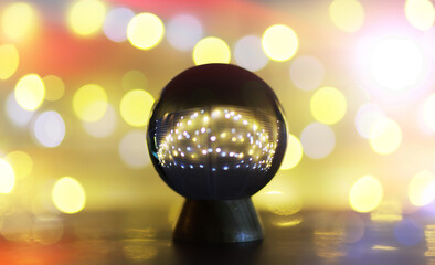 Crystal Ball on the table with bokeh, lights behind. Glass ball with colorful bokeh light, prediction concept.