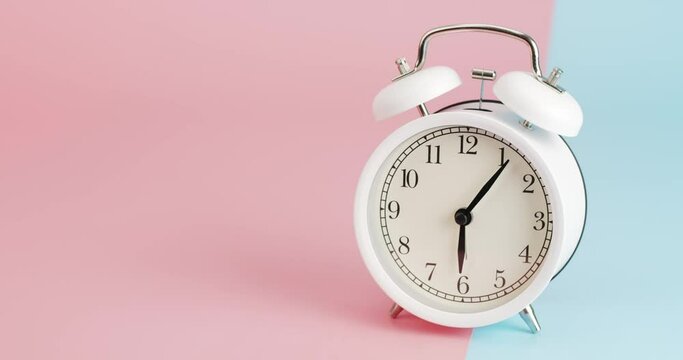 Time lapse White alarm clock shows 6 o'clock. The clock shows the elapsed time on the two tone background.